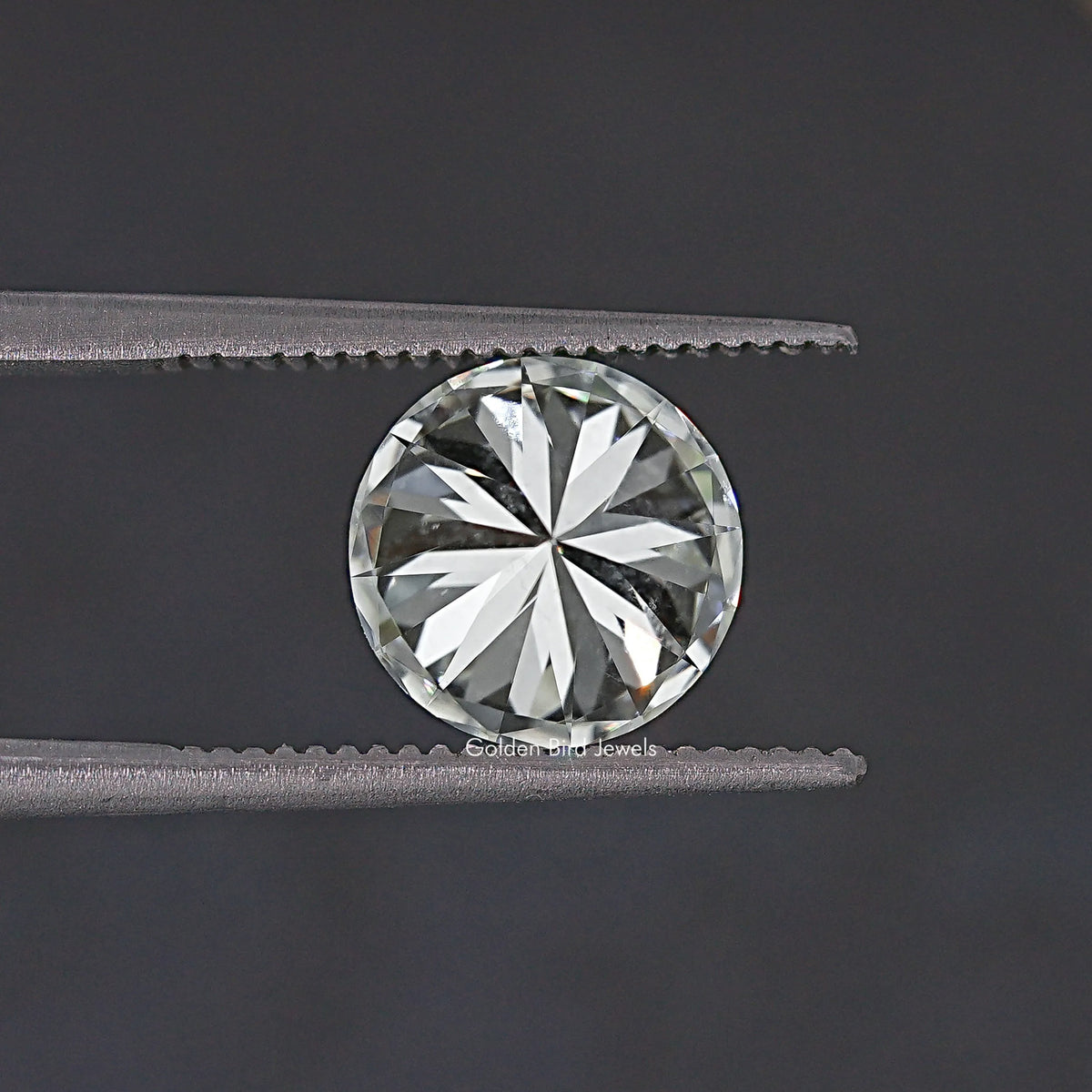 Round moissanite loose stone held between tweezers, starburst facet pattern, clear.