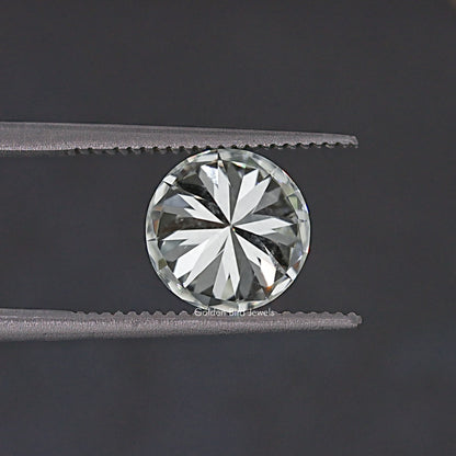 Round moissanite loose stone held between tweezers, starburst facet pattern, clear.