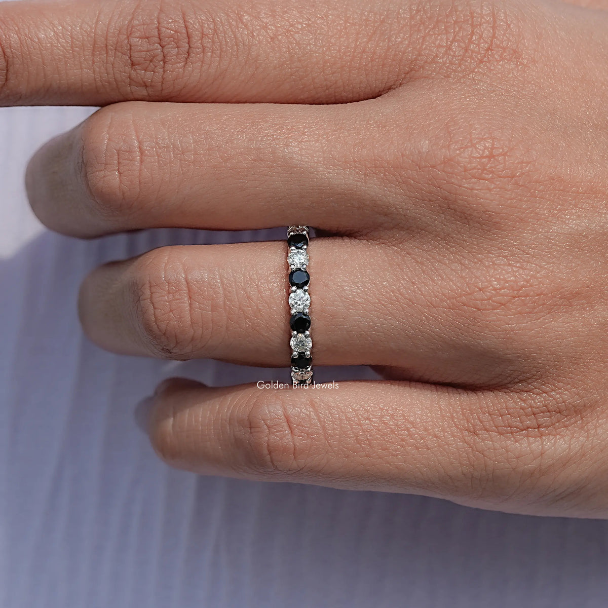 Silver eternity band viewed from the side with alternating dark and clear rounds