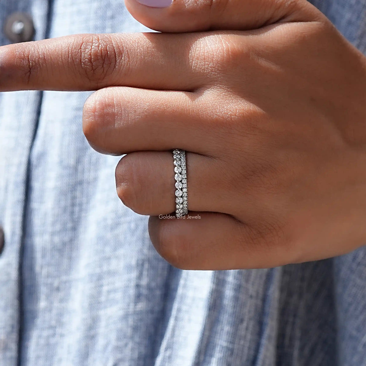 Silver round-stone eternity band ring wrapped around the finger near a sleeve