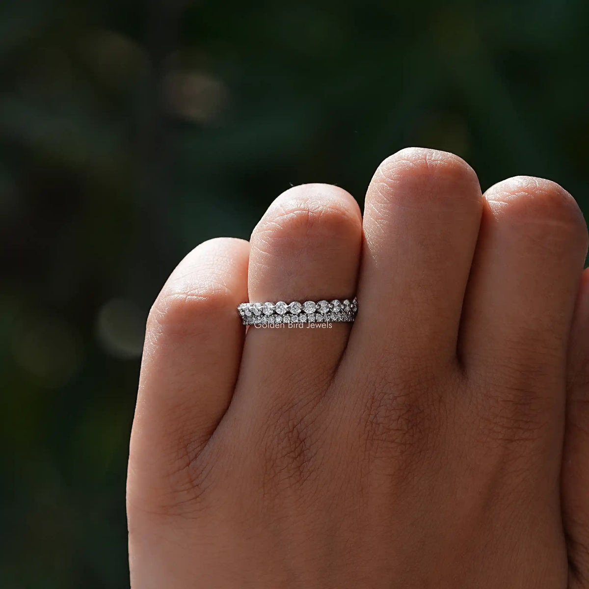Silver two-row eternity band ring with small round stones on an open hand