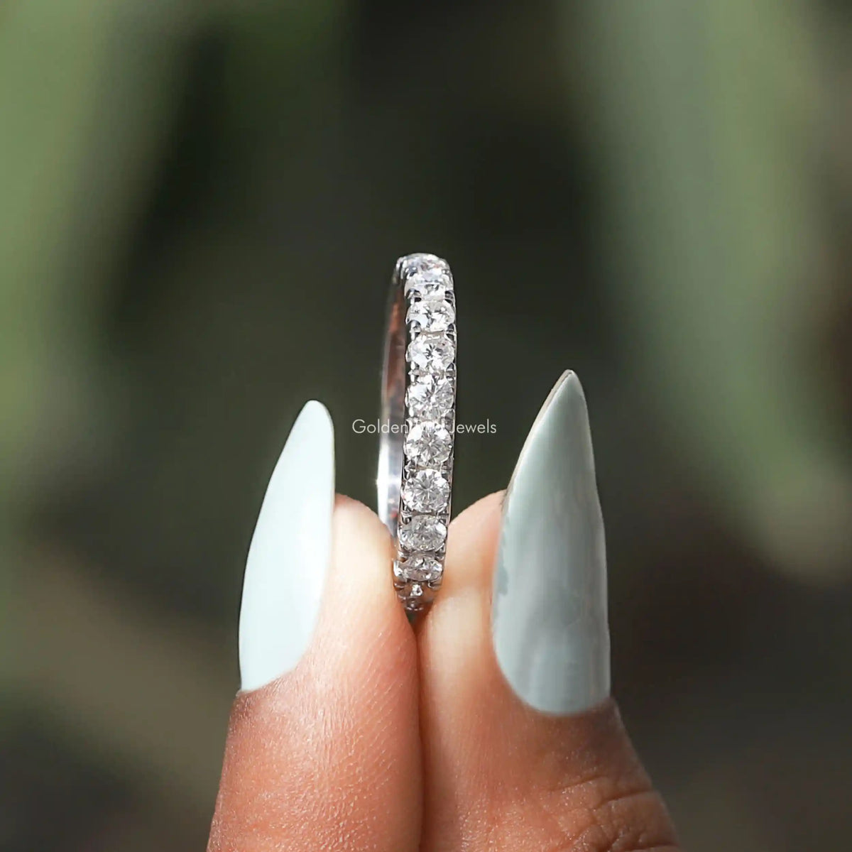 Vertical view of sterling silver eternity band with prong-set round moissanite stones