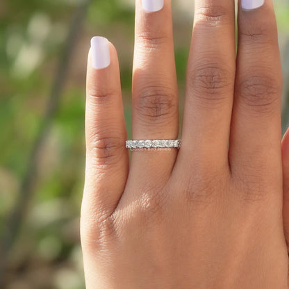 Round moissanite full eternity wedding band on finger, silver-toned with round stones