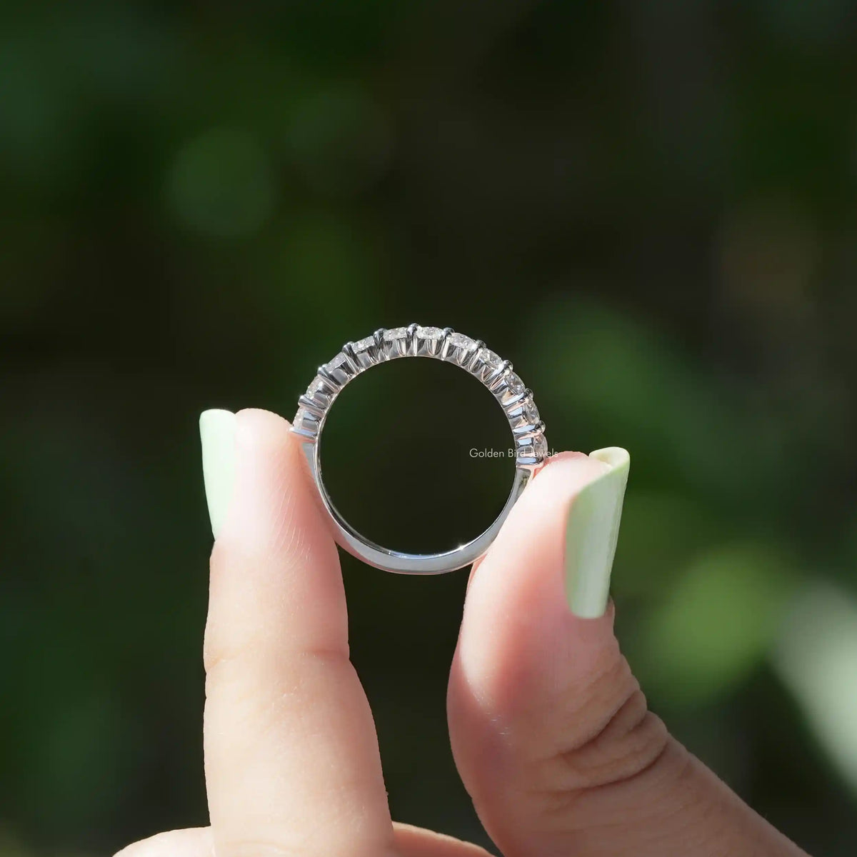 Silver half-eternity band ring with round-cut stones, worn on a hand