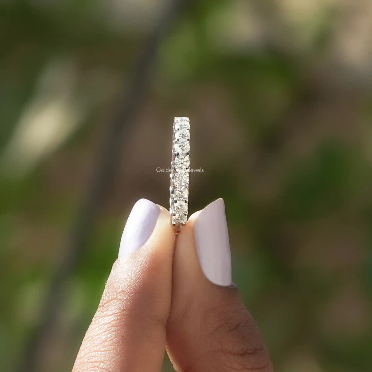 Round moissanite full eternity wedding band upright on finger, silver-toned with sparkling stones