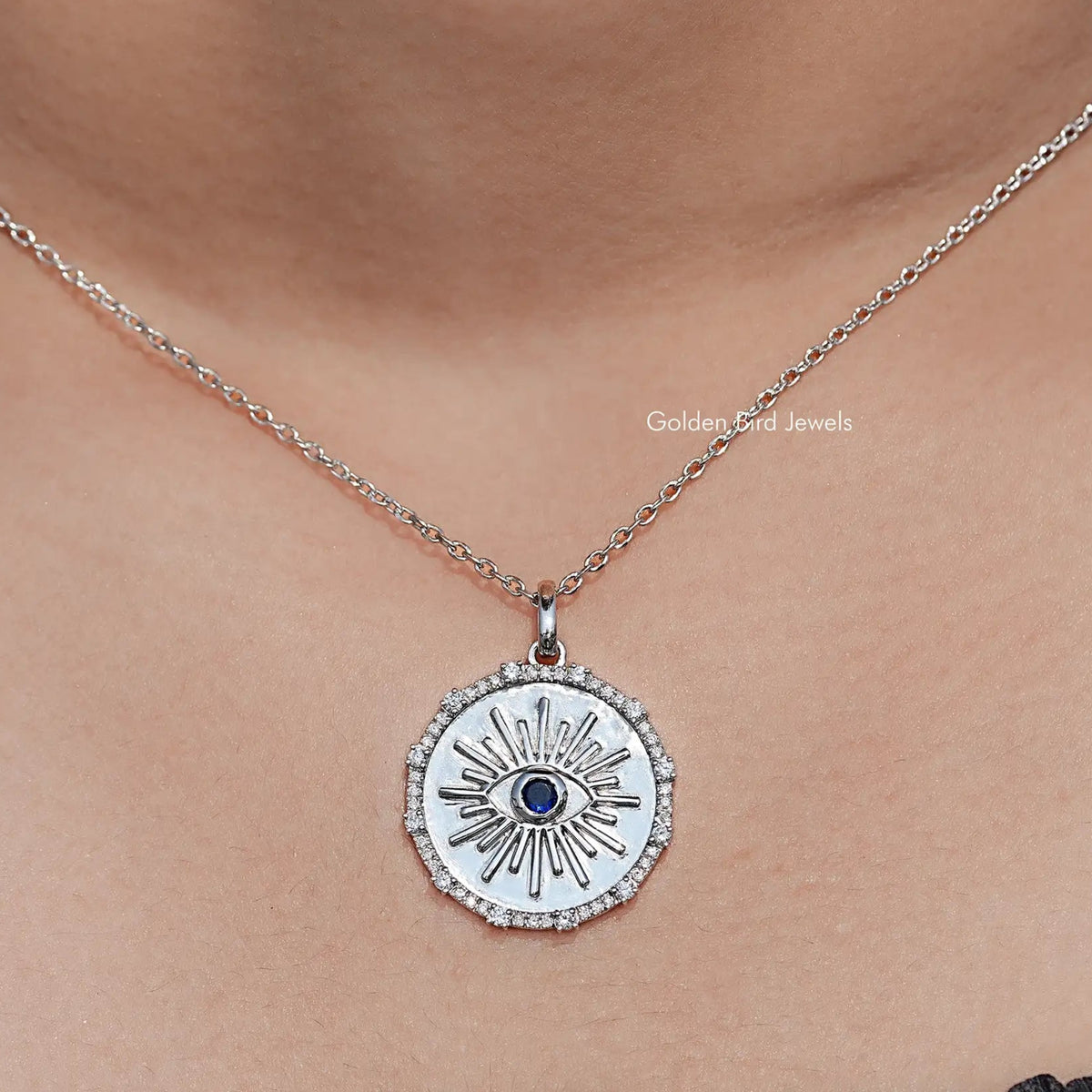 Round evil eye halo pendant with blue gemstone center on a silver chain