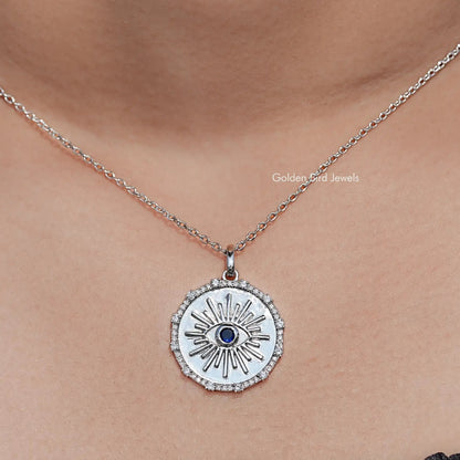 Round evil eye halo pendant with blue gemstone center on a silver chain