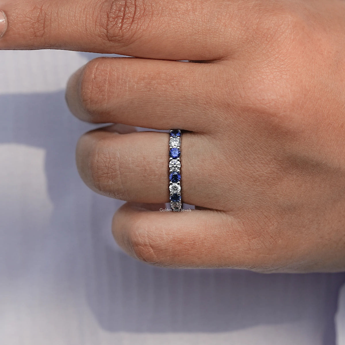 Close-up of eternity wedding band side showing row of blue round gemstones