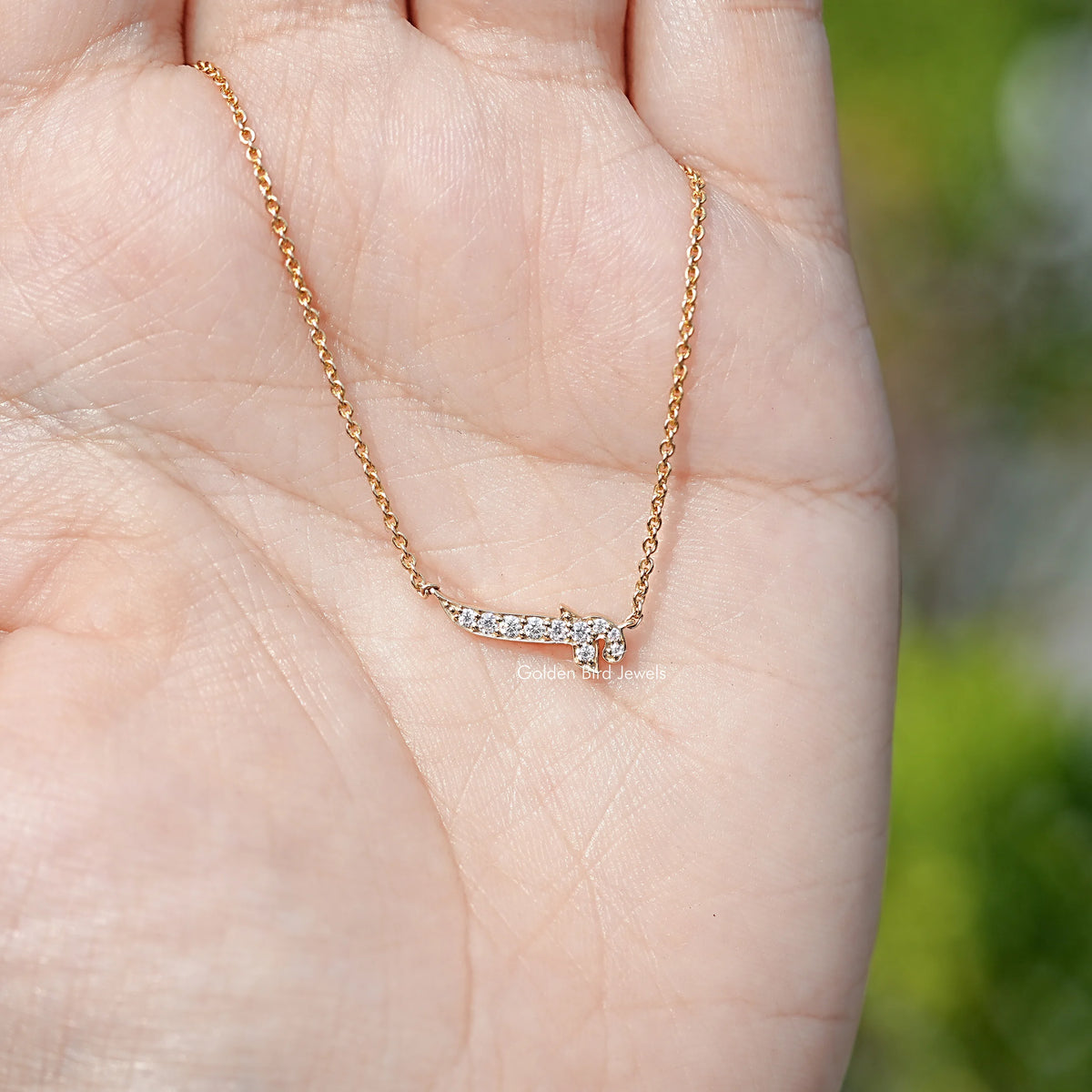 Gold-tone initial pendant necklace shown on an open palm, close-up.