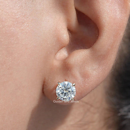 Round moissanite stud earring on ear, small gold-tone bezel setting