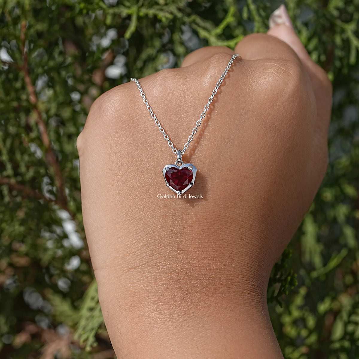 Red heart solitaire pendant necklace on silver chain, worn on upper arm