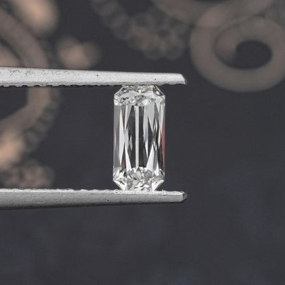 Rectangular lab-grown diamond with scissors-cut facets, held in metal tweezers