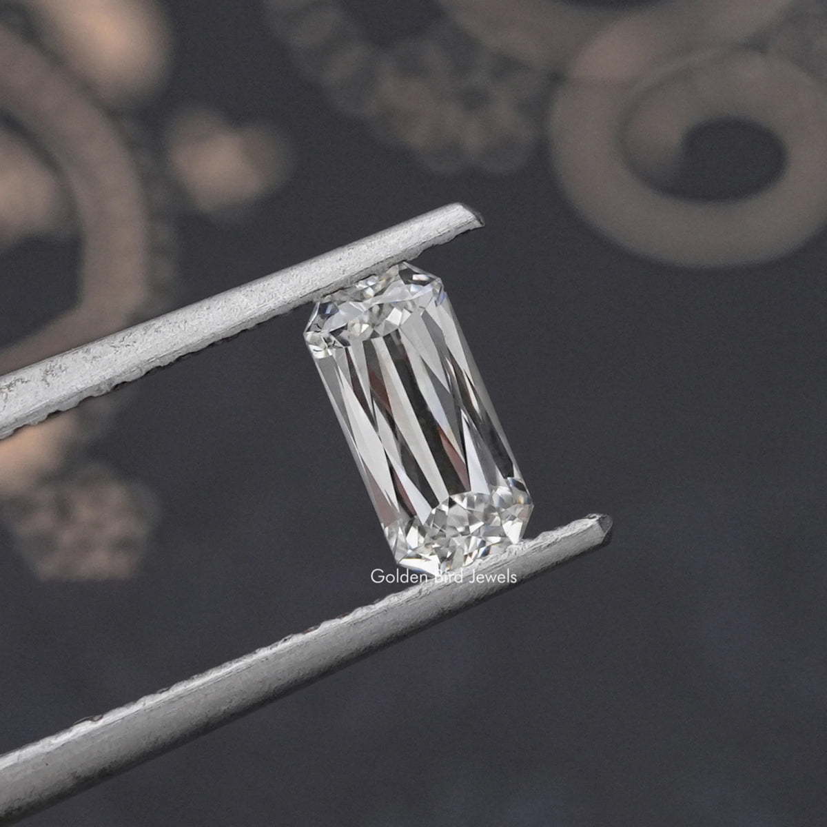 Rectangular lab-grown diamond with bright facet reflections, held between tweezers