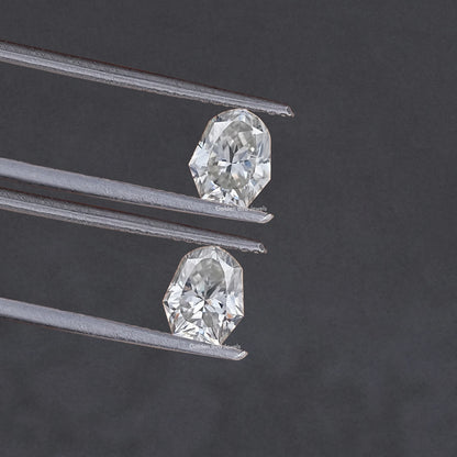Shield-cut moissanite stones pair in metal prongs, close-up side angle