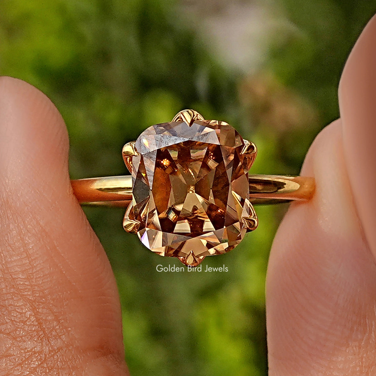 Close-up of gold cushion-cut solitaire ring, prong-set gemstone centerpiece