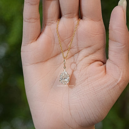 Gold-tone chain with pear-cut moissanite teardrop solitaire pendant in palm
