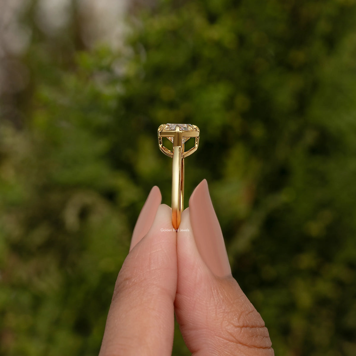 Oval moissanite solitaire ring side view with raised prongs and gold-tone band.