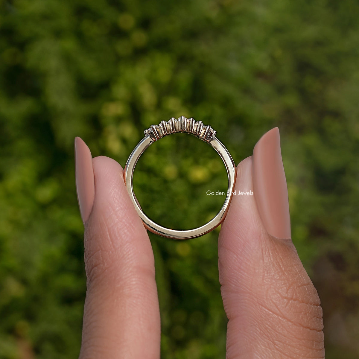 Curved wedding band ring viewed from front, baguette-cut stones set around top