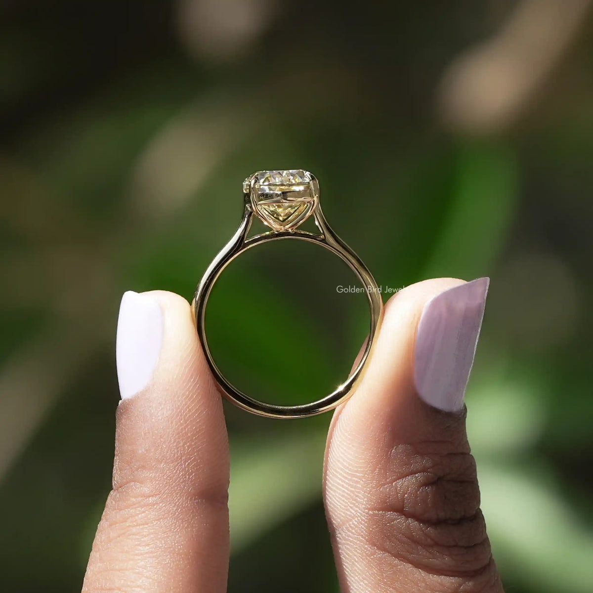 Back View of Solitaire Oval Cut Moissanite Engagement Ring In two fingers