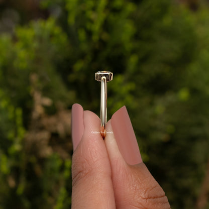 Gold-tone ring top view with emerald-cut lab diamond prong-set on a slim band