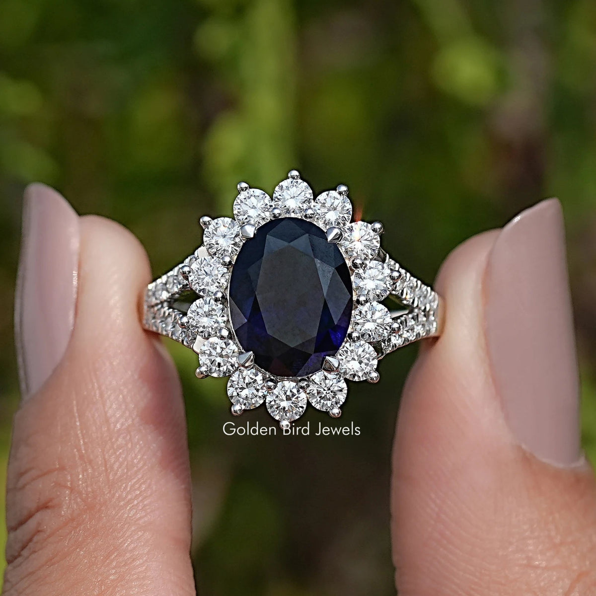 Large oval dark sapphire halo ring with sparkling cluster setting