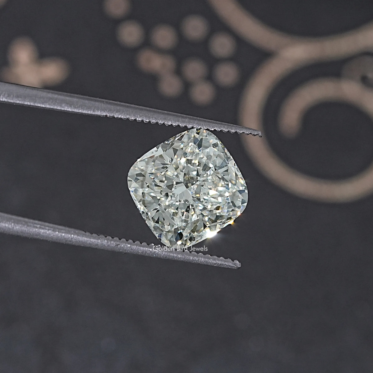 Loose cushion-cut lab diamond held in metal tweezers, bright faceted stone