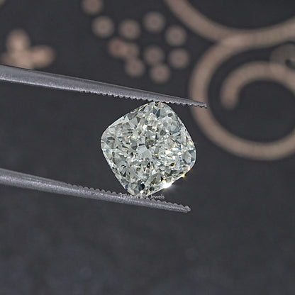 Loose cushion-cut lab diamond held in metal tweezers, bright faceted stone
