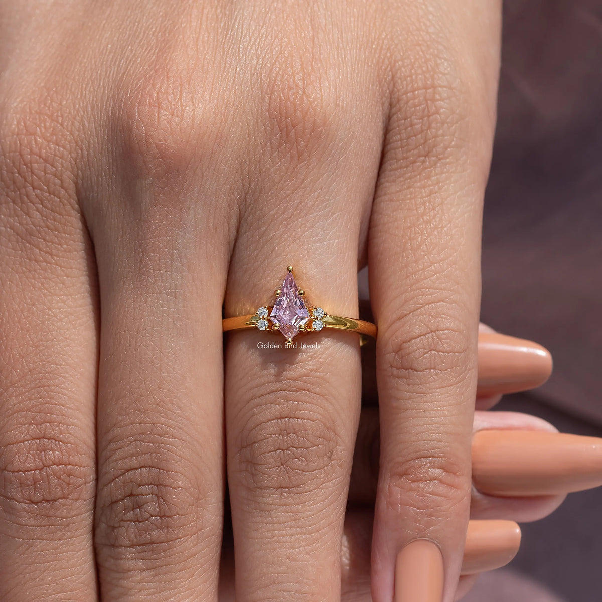Gold engagement ring featuring a pink kite-cut gemstone on a slim band