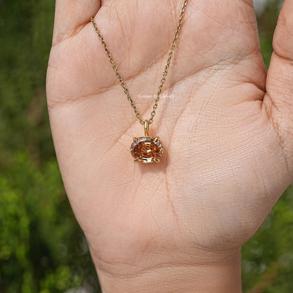 Champagne oval moissanite pendant on gold chain, held in open hand