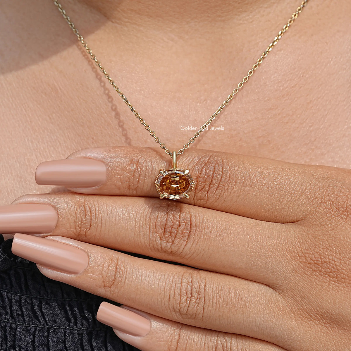 Champagne oval moissanite pendant on gold chain, resting over fingers