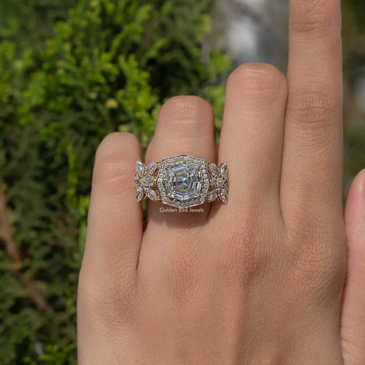 Cushion-cut moissanite ring with ornate halo, gold-tone band on finger