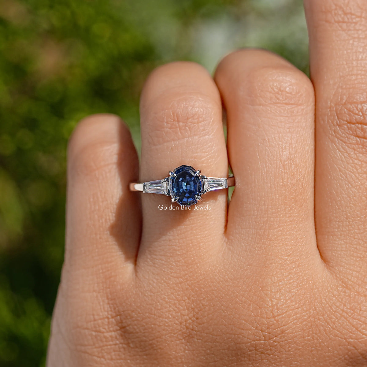 Blue oval three-stone ring with baguette side stones, polished silver band