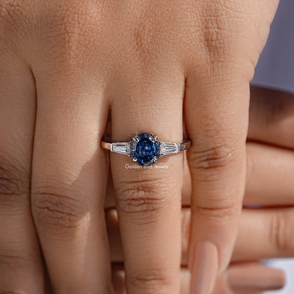 Three-stone moissanite ring with blue oval center and baguette side stones, silver