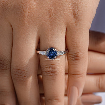 Three-stone moissanite ring with blue oval center and baguette side stones, silver