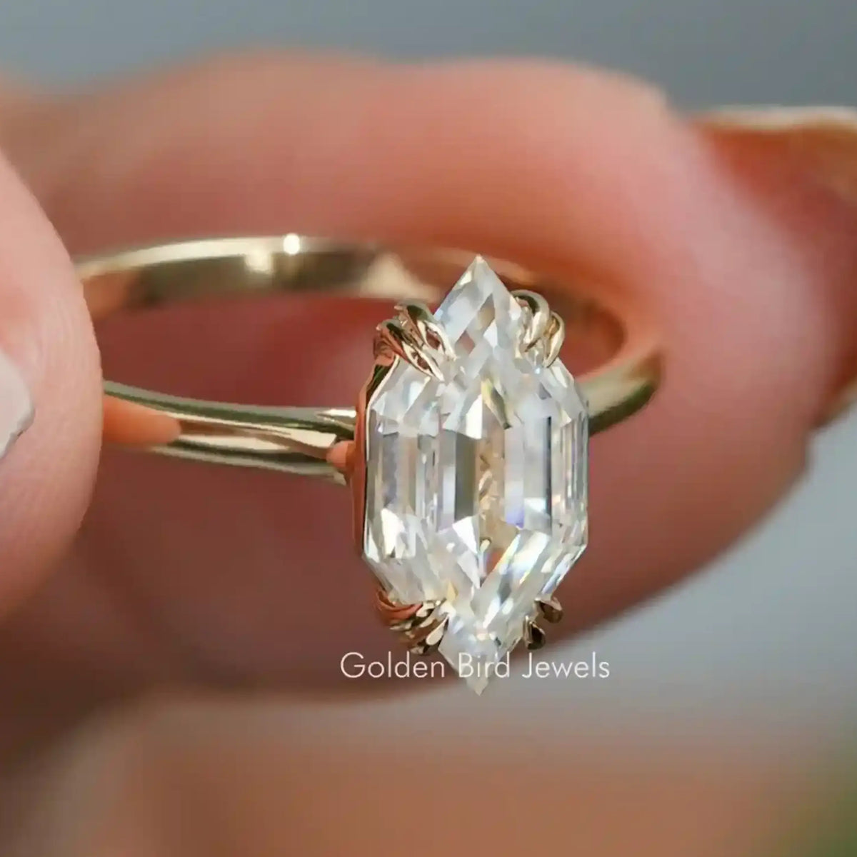 Gold-toned ring with oval marquise moissanite center stone, step-cut facets