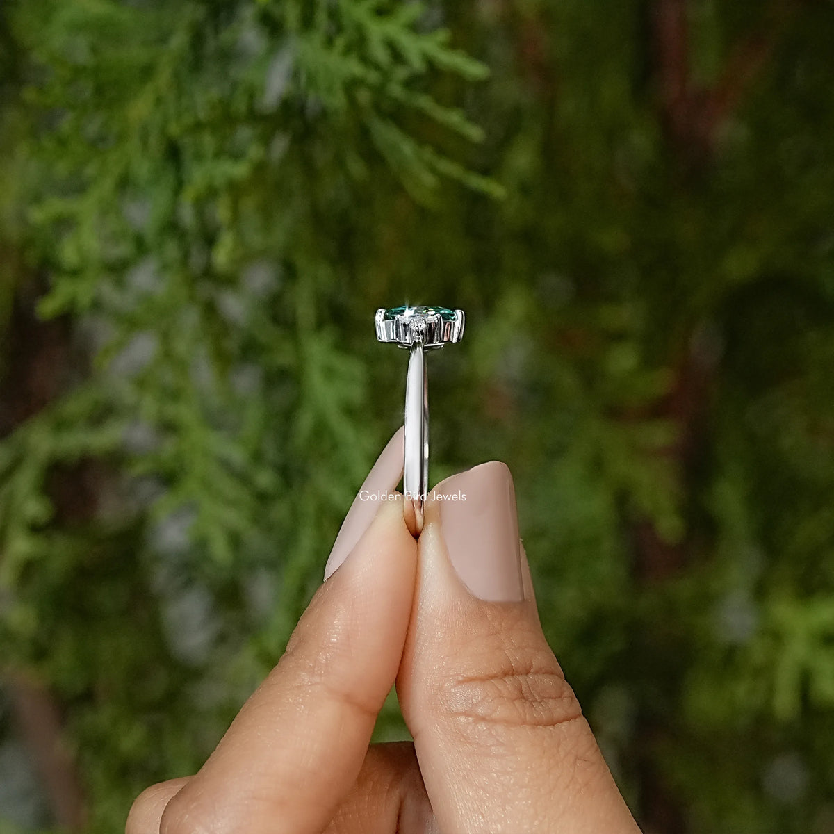 Three-stone engagement ring upright view, green marquise center with side stones on band