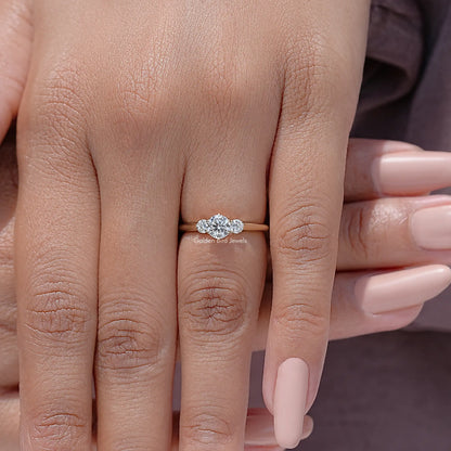 Three-stone round diamond engagement ring on finger, small center and side stones