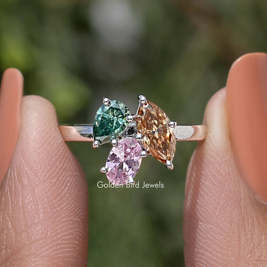 Three-stone engagement ring with green center stone, pink and amber side stones