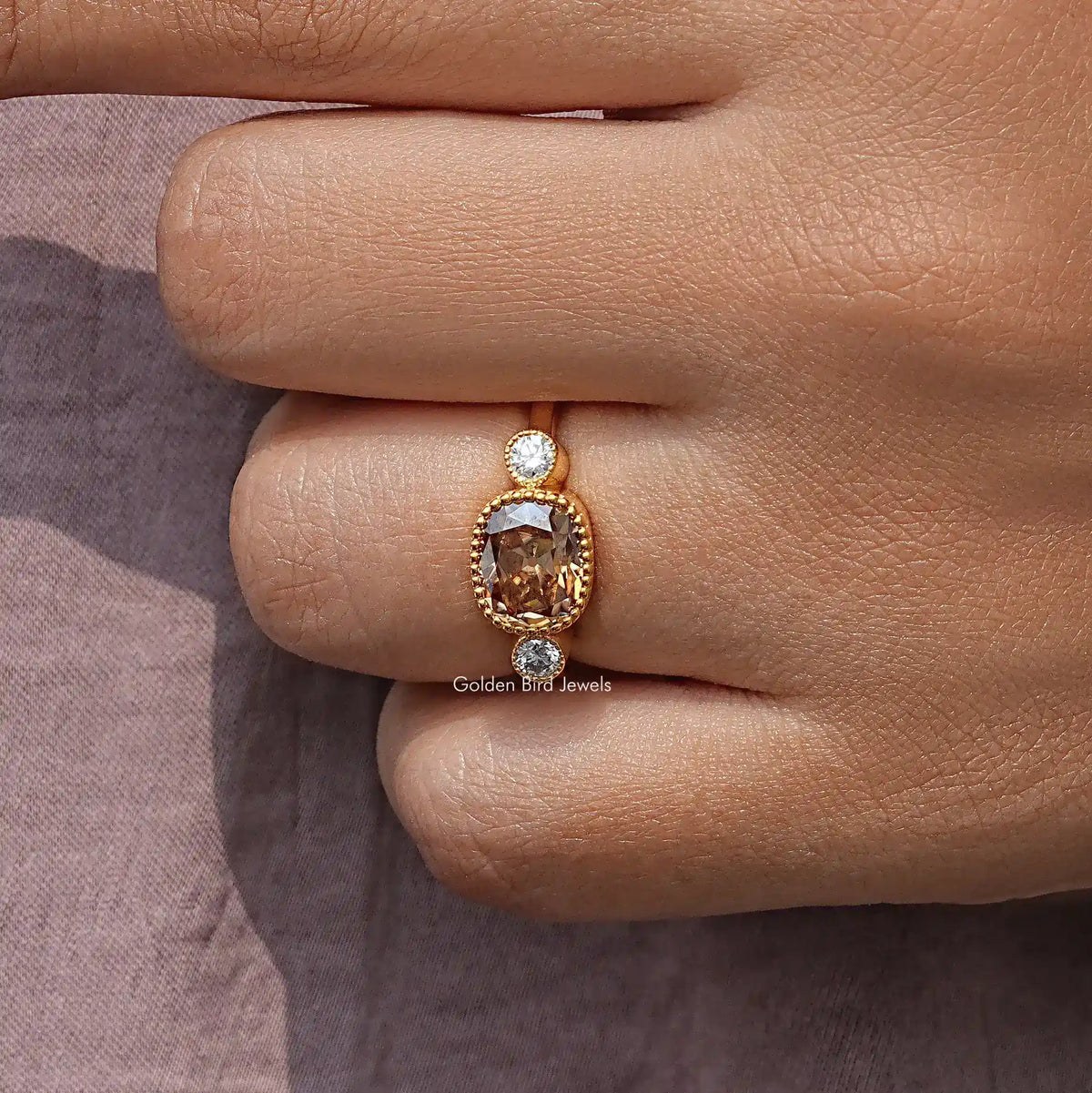 Yellow gold ring with round side diamond and cushion-cut center gemstone in prongs