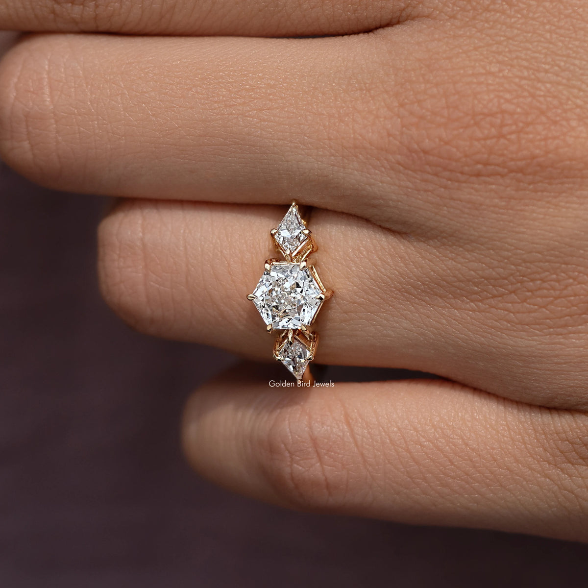 Three-stone diamond ring side view with prongs and faceted stones, yellow gold