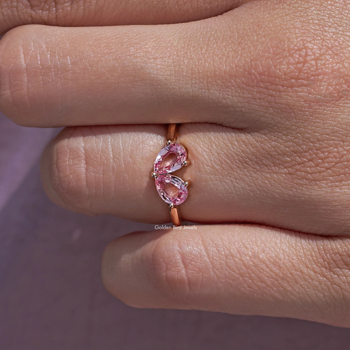Close-up of pink pear-cut lab gemstone toi et moi ring with two prong-set stones
