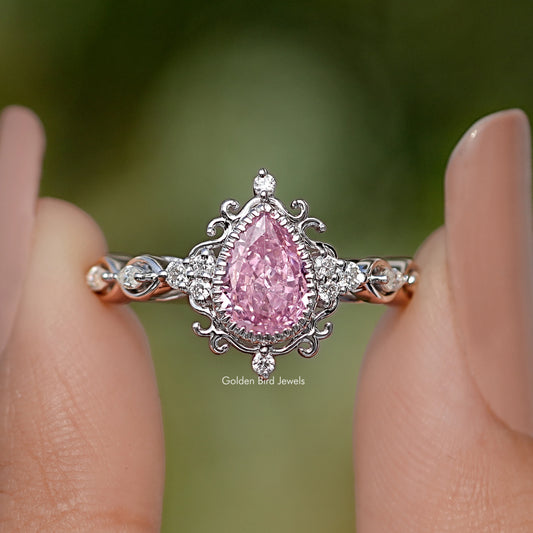 Close-up of pink pear-cut gemstone ring with ornate halo and twisted shank