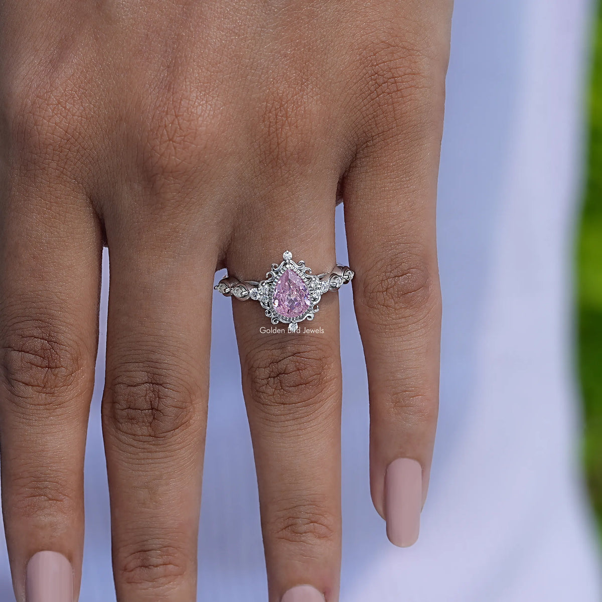 Pink pear-cut gemstone halo ring with twisted band and prong-set sparkle details