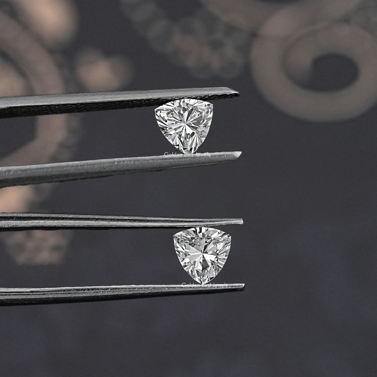 Trillion-cut lab-grown diamonds set in metal tweezers, two triangular stones