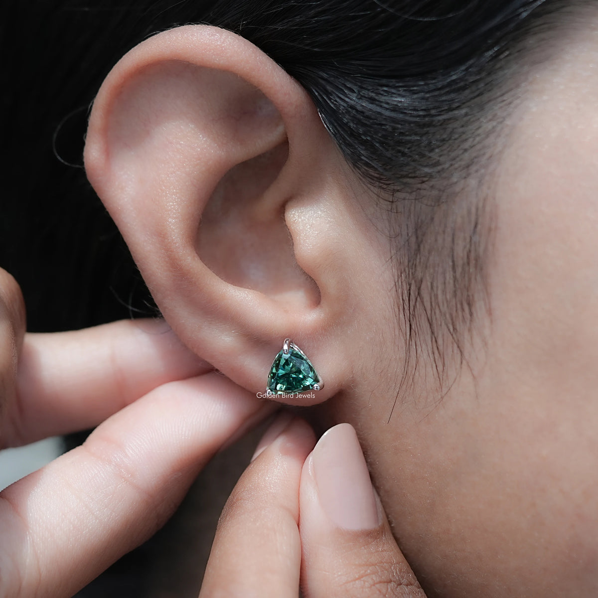 Dark green trillion-cut moissanite stud earrings viewed from the side
