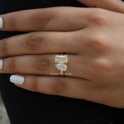Toi et moi ring on hand with gold-toned band and prong-set cushion emerald-cut stone