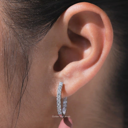 Round-cut moissanite huggie hoop earring on ear, vertical stone-set detail
