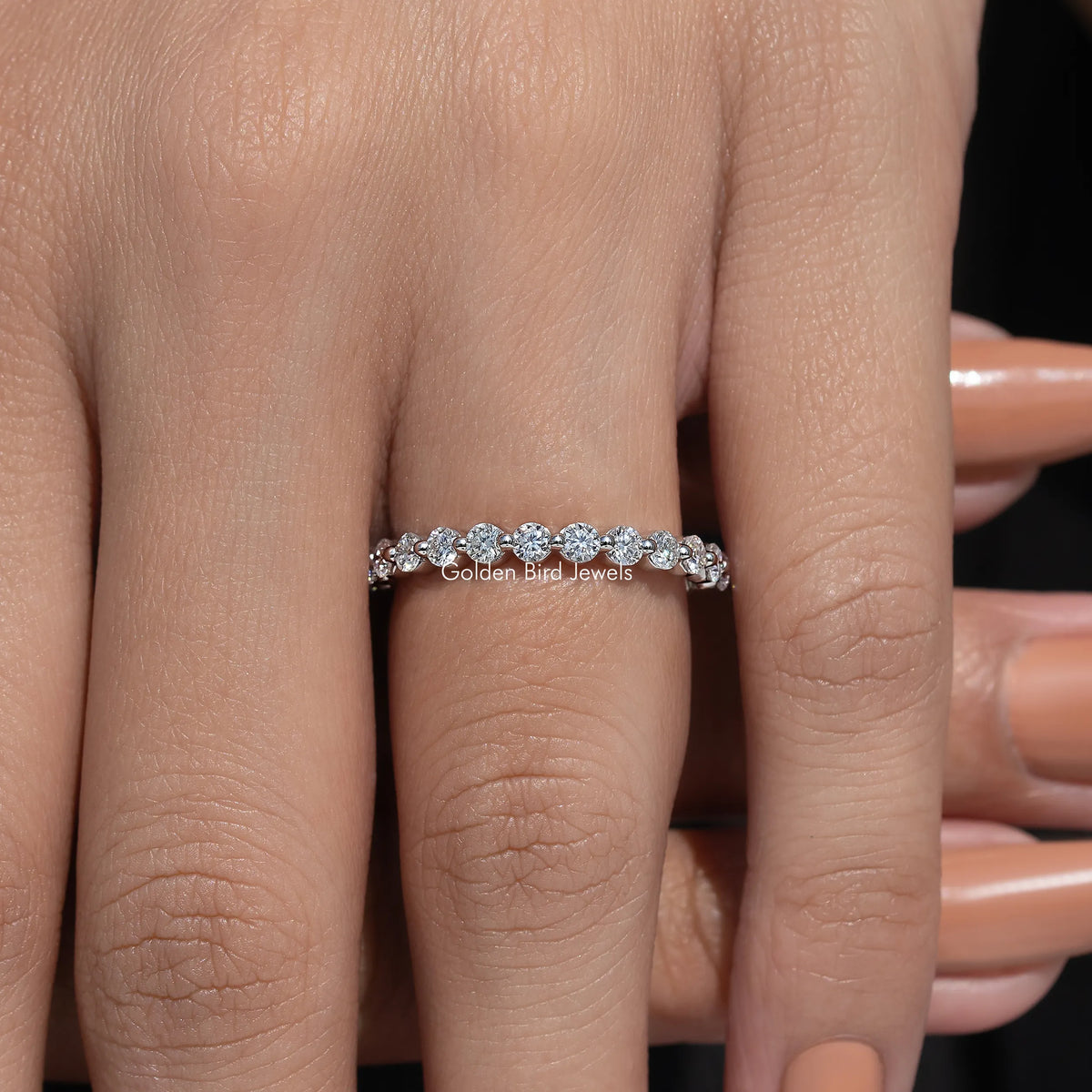 Silver-tone half eternity band with round moissanite stones, worn on finger