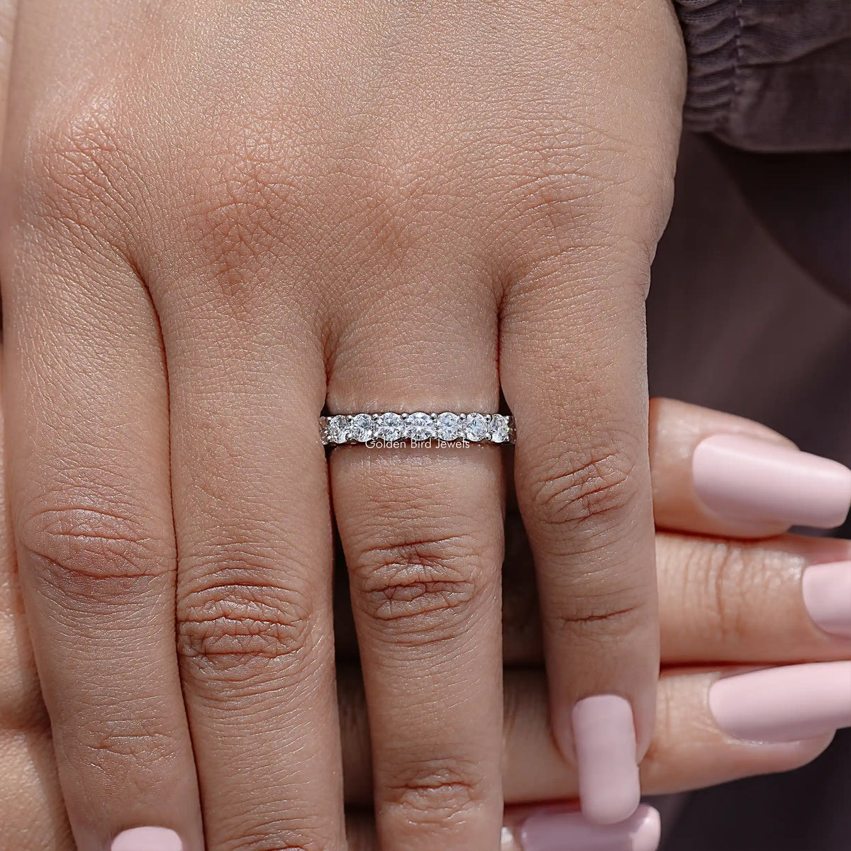 Half eternity moissanite band with clear round-cut stones on hand, centered view