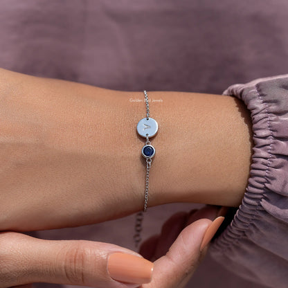 Close view of sterling silver bracelet with light blue initial A disc and dark blue gem